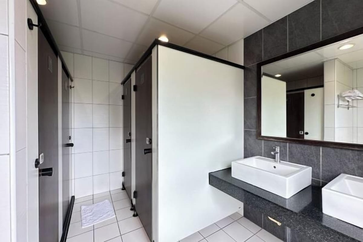 Ein modernes Badezimmer mit einem großen Spiegel, zwei Waschbecken und einer Duschkabine.