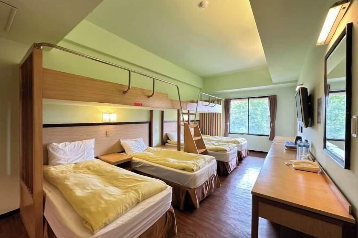Une chambre avec des lits superposés, un bureau et une grande fenêtre.