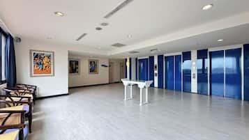 Una habitación amplia con una larga mesa y sillas, un piano y obras de arte en las paredes.