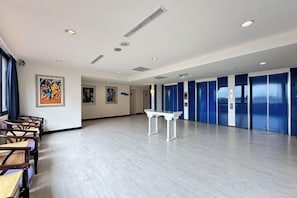 Una habitación amplia con una larga mesa y sillas, un piano y obras de arte en las paredes.