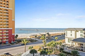 Ein Küstenhotel mit Blick auf den Strand, einem Steg und einer Uferstraße mit Palmen.
