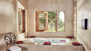 Un cuarto de spa con una bañera grande, contraventanas de madera y vistas al exterior.