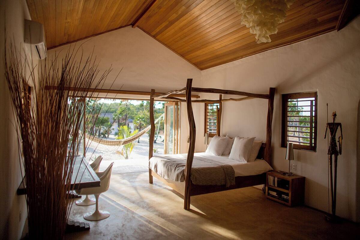 Une chambre à coucher avec un lit à baldaquin, un hamac et une vue sur l’extérieur.