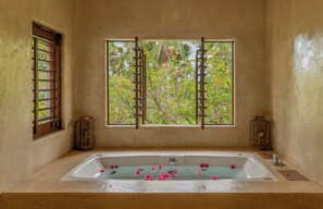A bathroom with a bathtub, a window with a view of greenery, and two wall-mounted lanterns. - Villa Paz - La Villa Group (Camocim)