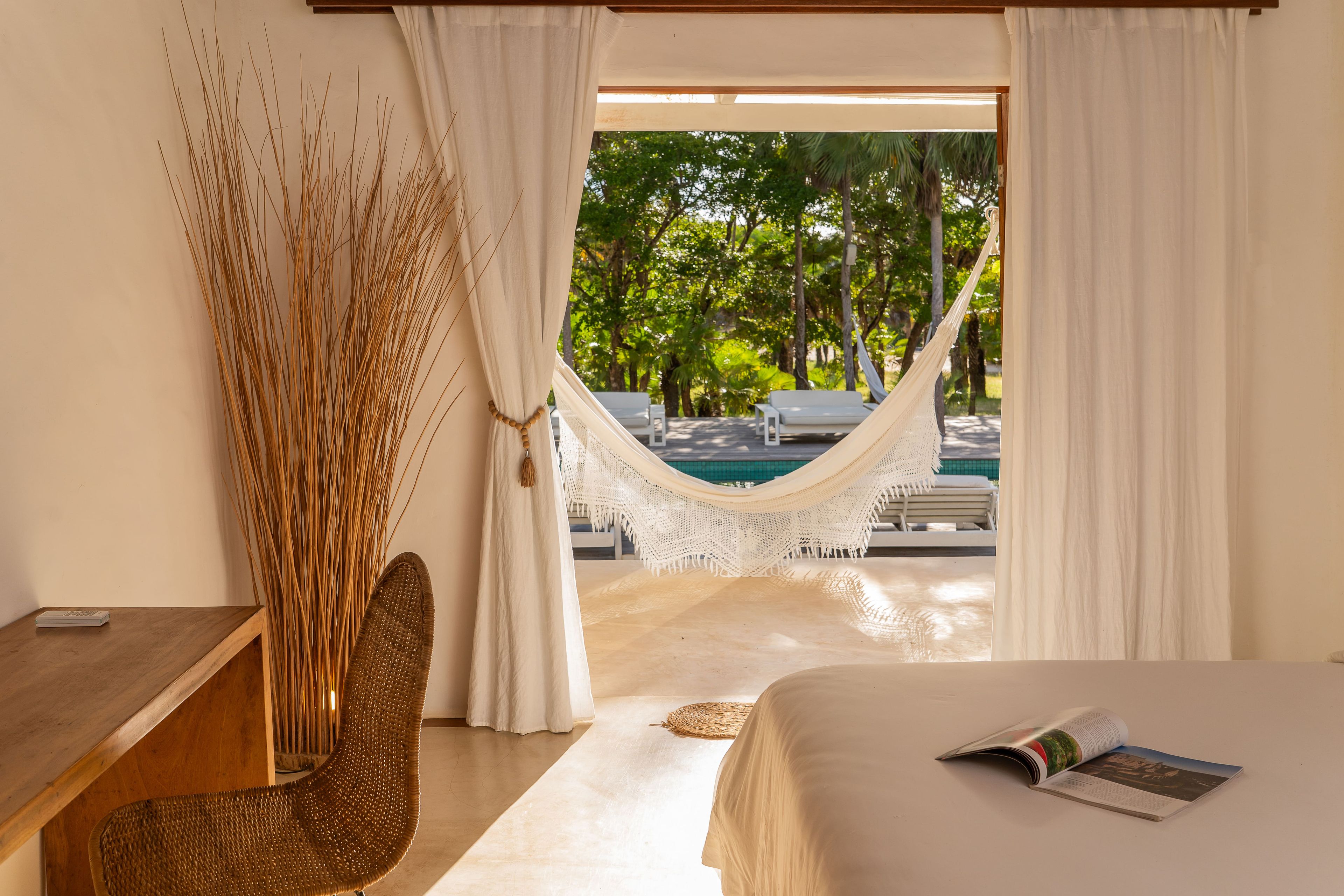 A bedroom with a view of a pool and outdoor seating.