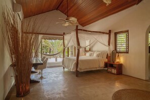 A bedroom with a four-poster bed, a hammock, and a bedside table with a lamp. - Villa Paz - La Villa Group (Camocim)