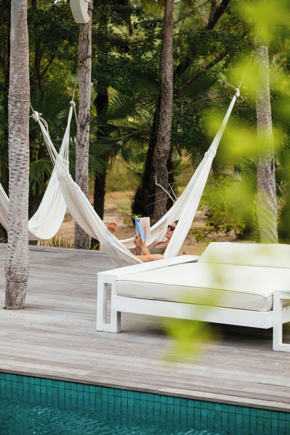 A hammock tied between trees, a white lounge chair, and a poolside setting. - Villa Paz - La Villa Group (Camocim)