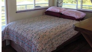 Un dormitorio con cama, ventana y vistas al exterior, y cabecero de madera.