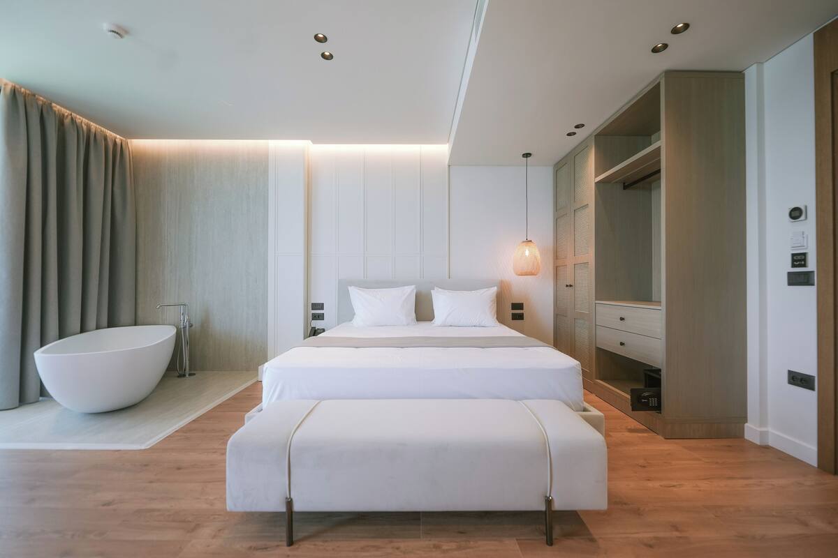 Une chambre d’hôtel moderne dotée d’un grand lit, d’une baignoire intégrée et d’un dressing.