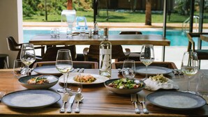 A dining table set for two with plates of food, glasses, and a bottle of wine. - Euro Hotel (Ksamil)