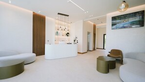 A modern reception area with a reception desk, seating, and a painting on the wall. - Euro Hotel (Ksamil)
