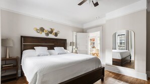 Una camera da letto con un letto grande, una ventola a soffitto e uno specchio a parete.