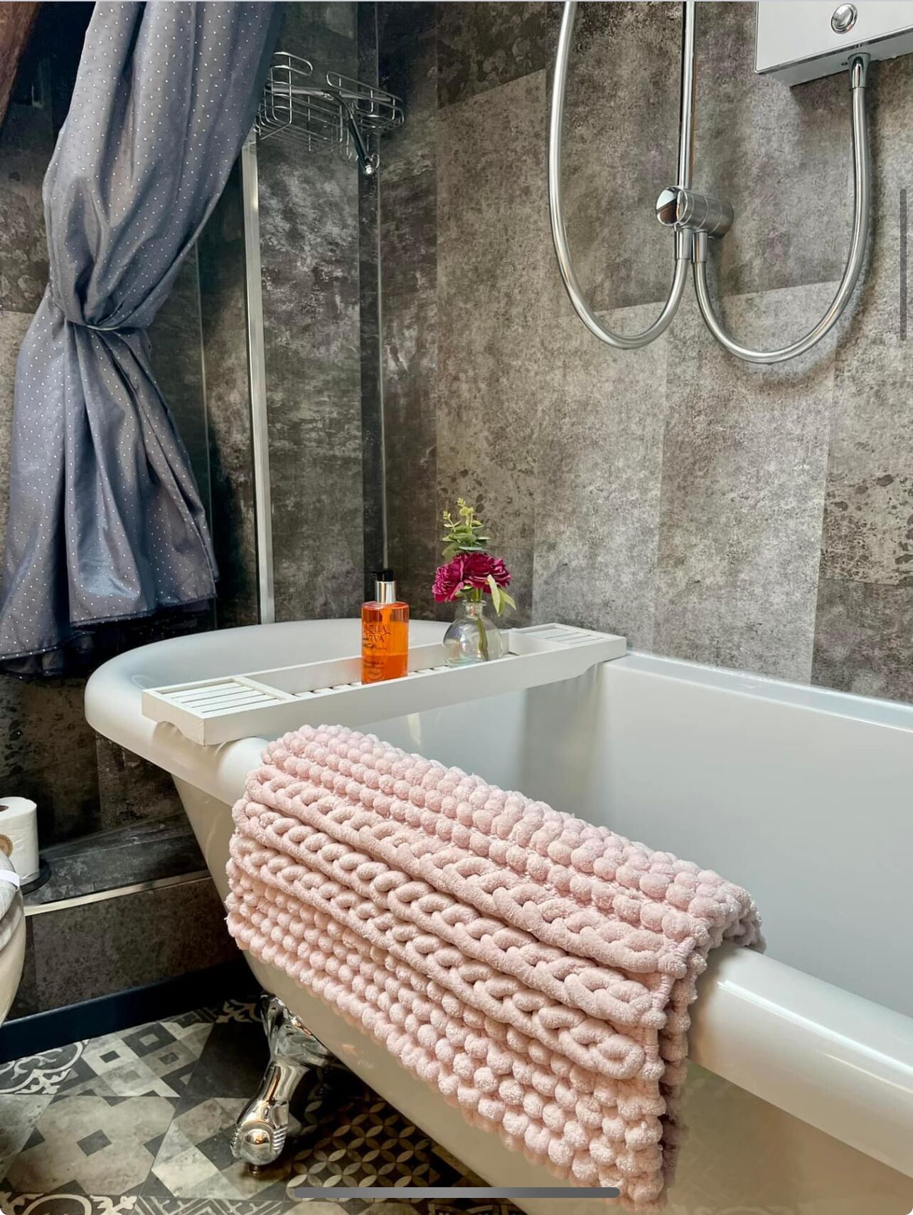 Un baño con una bañera blanca, ducha y un perchero para toallas.