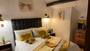 Quarto com uma cama grande, cabeceira, mesas de cabeceira e decoração na parede.