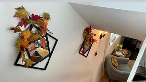 Uma escadaria com espelho fixado na parede e decoração com folhas de outono.