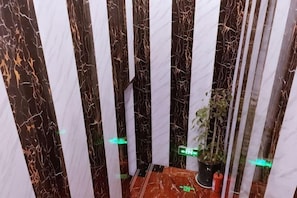 A narrow, enclosed space with vertical stripes, a potted plant, and a red object on the floor. - Tongling Junlai Hotel (Tongling)