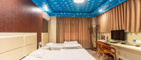 A hotel room with a bed, a desk, a chair, a television, and a window with curtains.