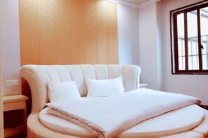 Ein Bett mit gebogenem Kopfteil, ein Nachttisch und ein Fenster mit Gitterstäben.