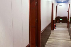Un pasillo con puertas de madera, un extintor y un detector de incendios en la pared.