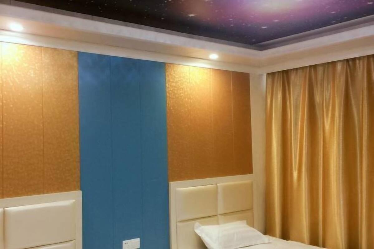 Una habitación de hotel con una cama, una pared con un panel azul y un techo con diseño de galaxia.