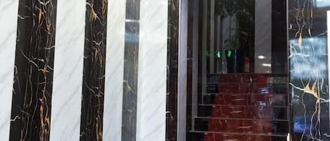 Uma escadaria de mármore com um tapete vermelho que leva a um andar superior.