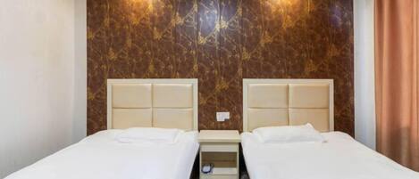 A hotel room with two beds, a marble-patterned wall, and a small bedside table.