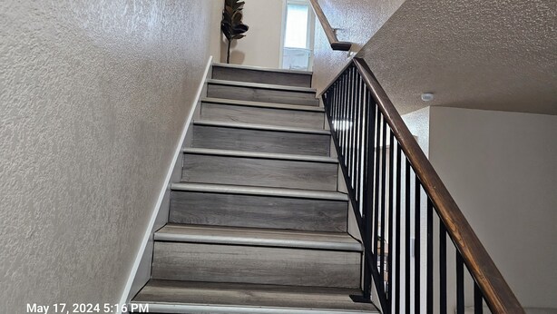 A staircase with wooden steps and a black metal railing. - Marine View Townhouse (Everett)