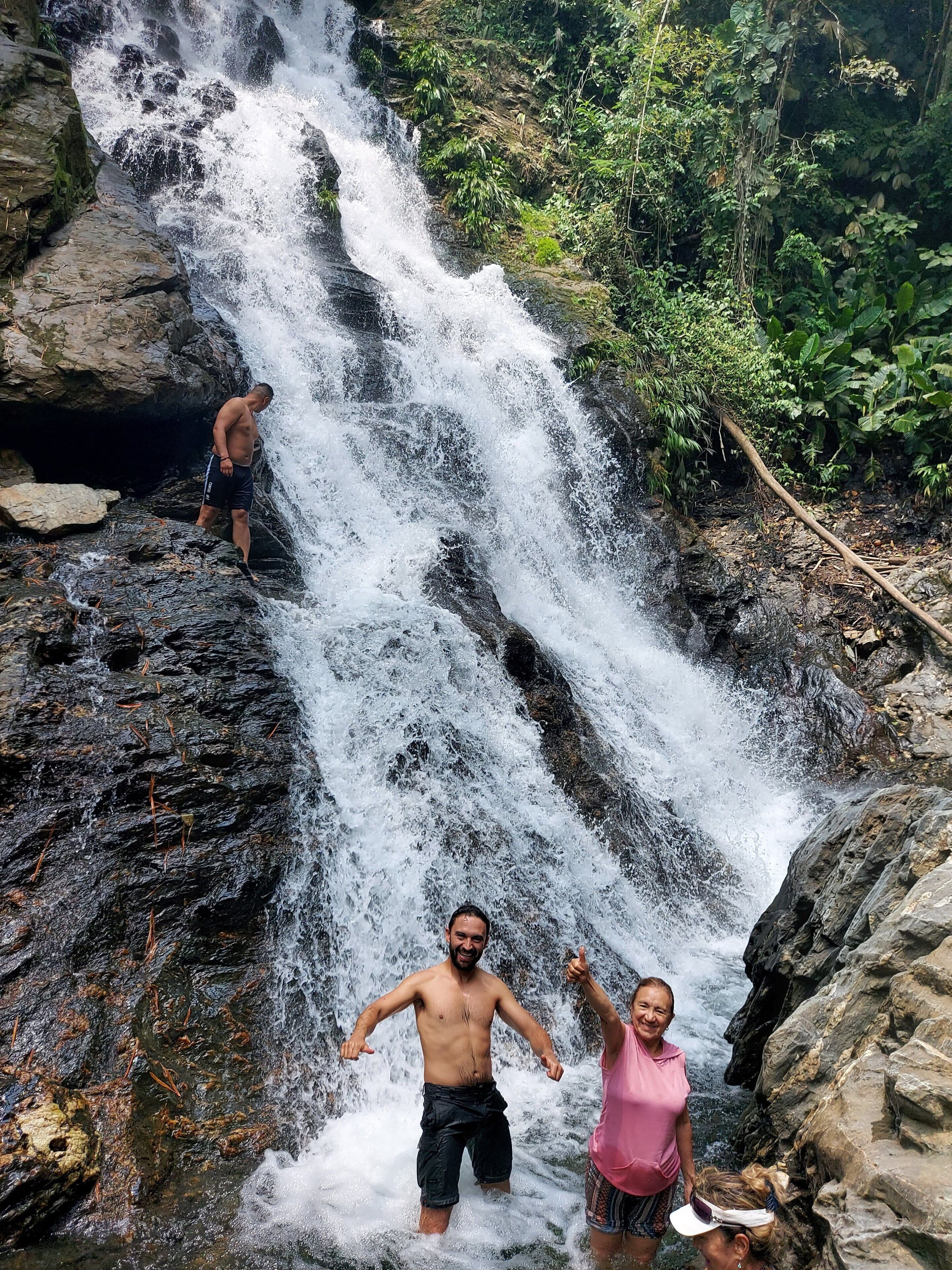 A waterfall in a natural setting with rocky terrain and lush greenery.