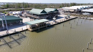 A waterfront property with a dock extending into a body of water, a covered seating area, and a building with a green roof.