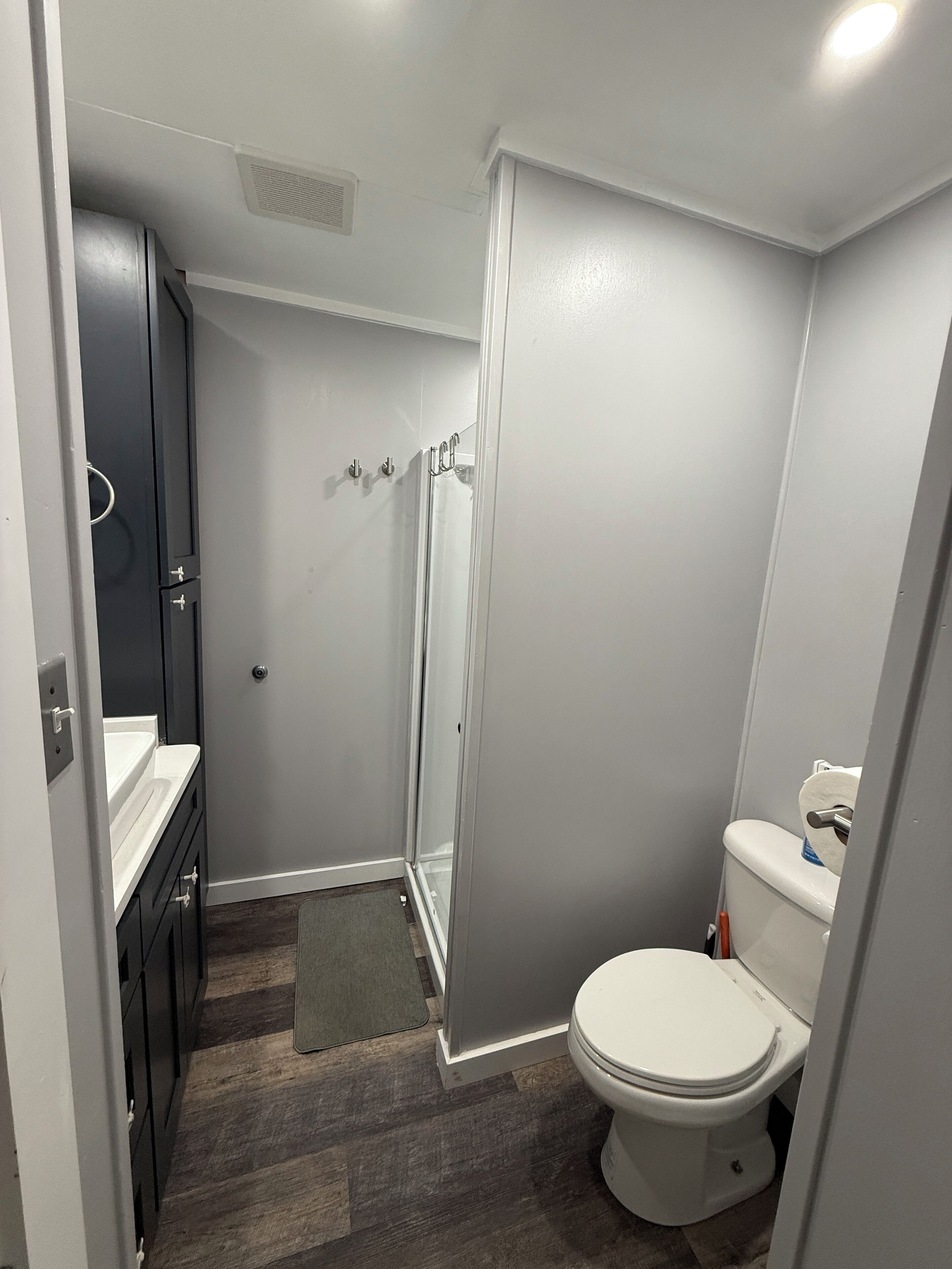 Baño compacto con ducha, inodoro y un pequeño tocador.