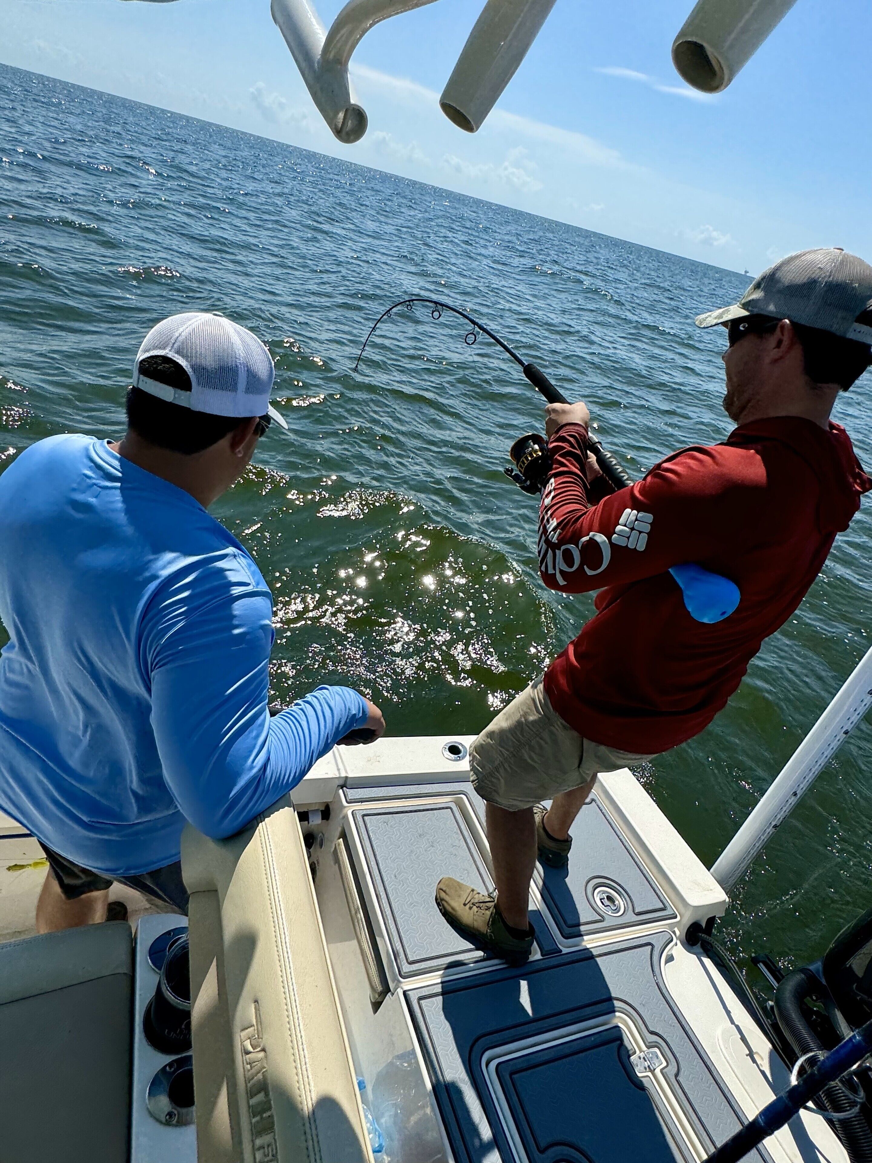 Two people fishing on a boat with a view of the ocean.