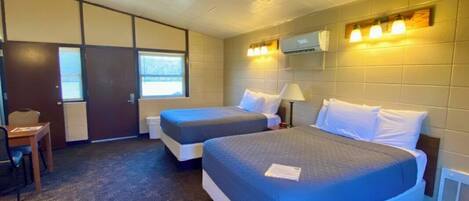 A hotel room with two beds, a desk, and a chair.