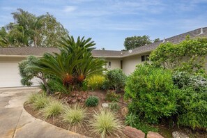 Una propiedad residencial con un jardín bien cuidado, un camino de entrada y una casa con garaje.