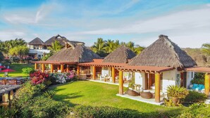 Un resort con edifici a tetto di paglia, posti a sedere all'aperto e una vegetazione lussureggiante.