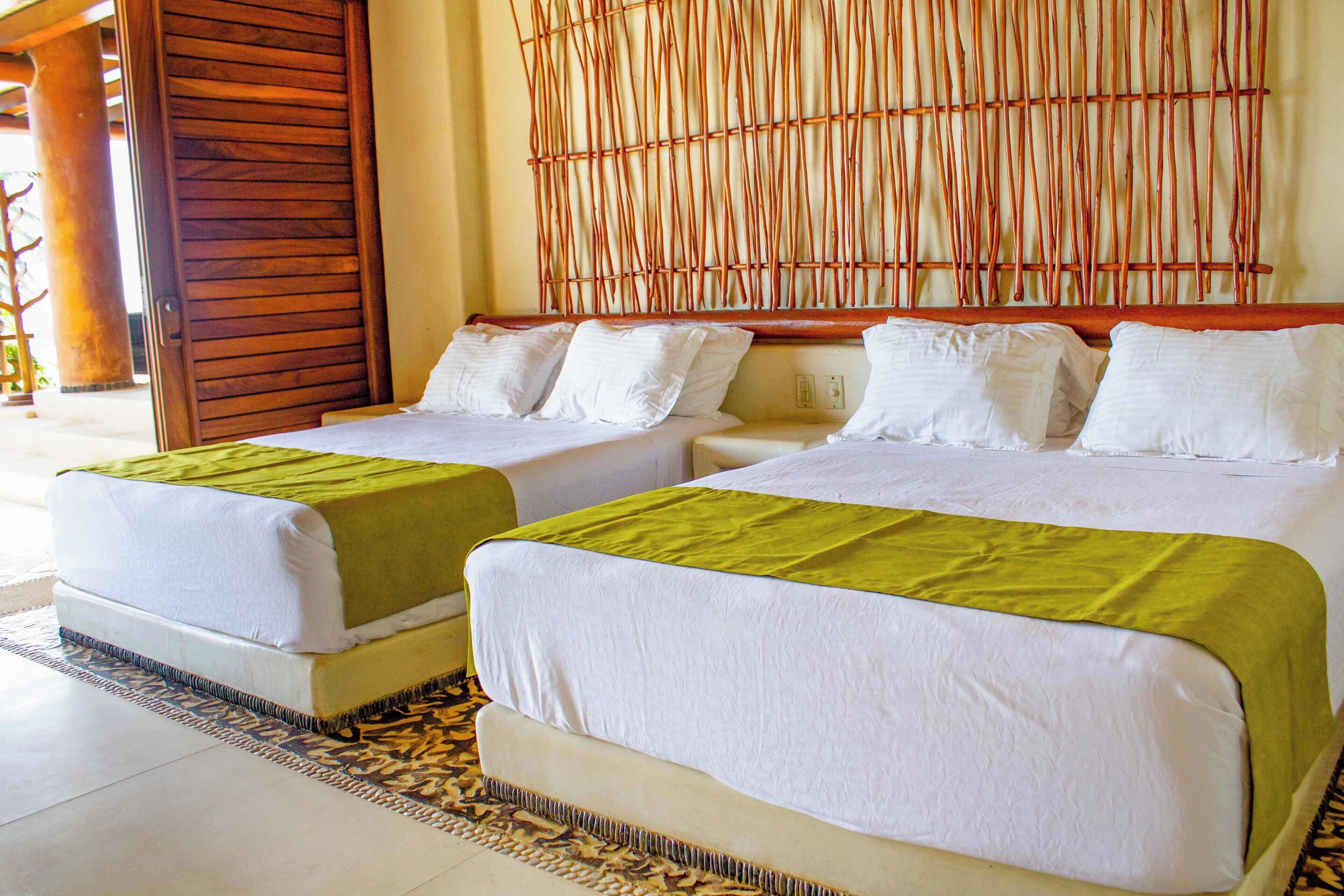 A hotel room with two beds, a bamboo wall, and a wooden door.