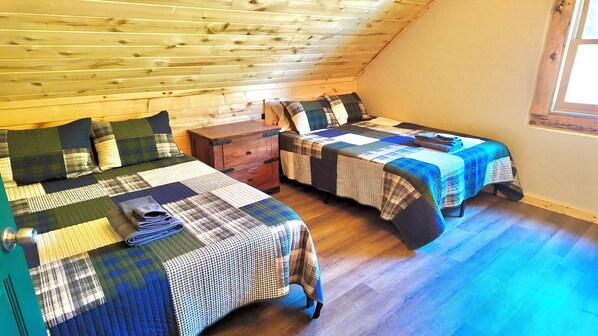 A cozy room with two beds, wooden walls, and a small wooden chest. - Creek Lodge + Off Grid + Family Centered (Dolores)