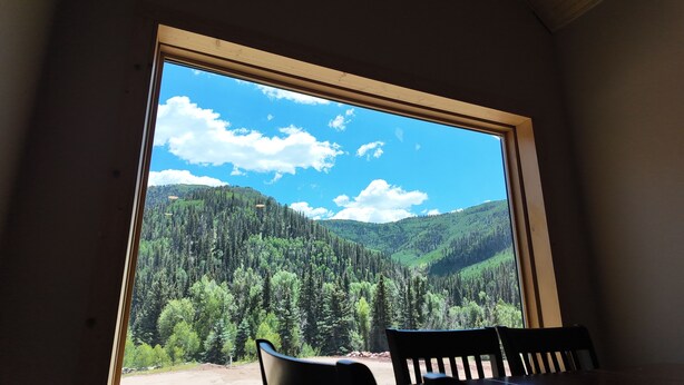 Una habitación con un amplio ventanal que ofrece vistas a una cadena montañosa boscosa.