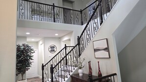 Un intérieur à plusieurs niveaux, avec un escalier, une plante en pot et un panneau fixé au mur.