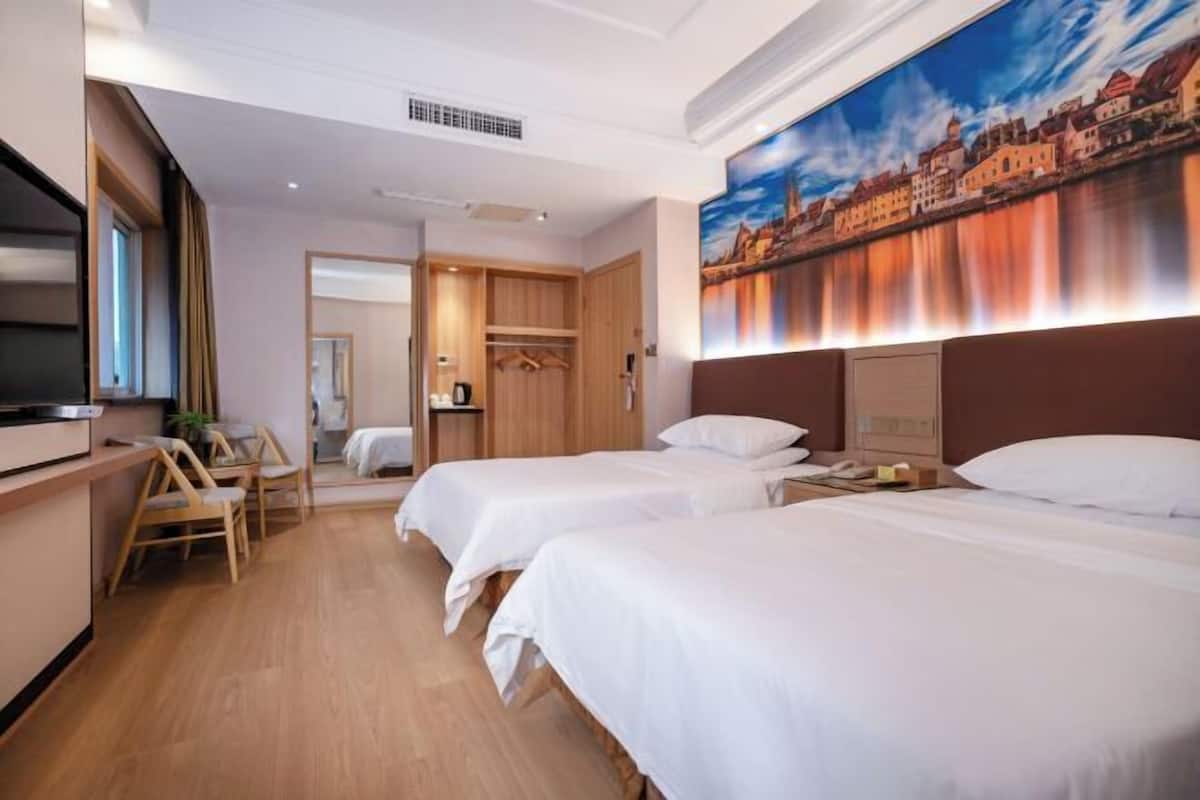 A hotel room with two beds, a desk, and a chair. There is a painting on the wall and a TV on the left side.