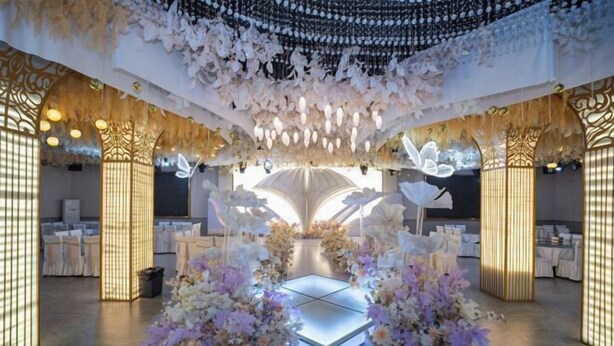 Ein Bereich für eine Hochzeitszeremonie mit erhöhter Plattform, Blumenschmuck und hängenden Dekorationen.