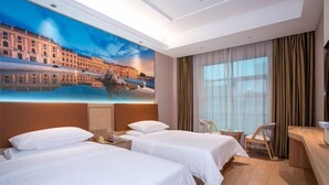 Et hotelværelse med to senge, et skrivebord, en stol og et stort vindue med gardiner.