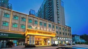 Ein Hotel mit einem markanten Eingang, mehreren Etagen und einem großen Gebäude im Hintergrund.