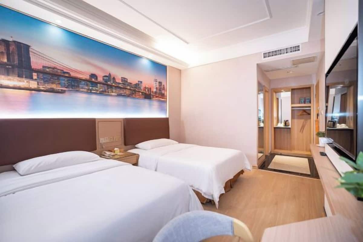 A hotel room with two beds, a large cityscape painting, a television, and a walk-in closet.