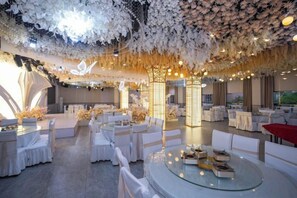 A spacious indoor venue with round tables and chairs, a high ceiling with floral decorations, and a modern interior design. - Vienna Hotel Chibi HIigh-speed Railway Station Branch (Chibi)