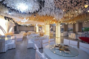 Un espacio interior amplio con mesas y sillas redondas, un techo alto decorado con motivos florales y una decoración de diseño moderno.