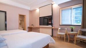 Et hotelværelse med to senge, et fjernsyn, et vindue og et lille bord med stole.