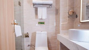 Et moderne badeværelse med toilet, glasvægs brusebad, vask og spejl.