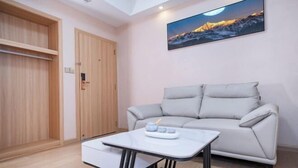 Ein Zimmer mit einer Couch, einem kleinen Tisch und einem Gemälde einer Berglandschaft.