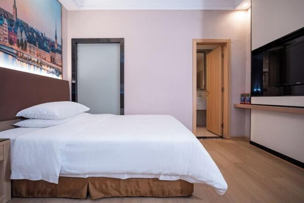 Et hotelværelse med en seng, et fjernsyn, et træskab og en dør til et badeværelse.