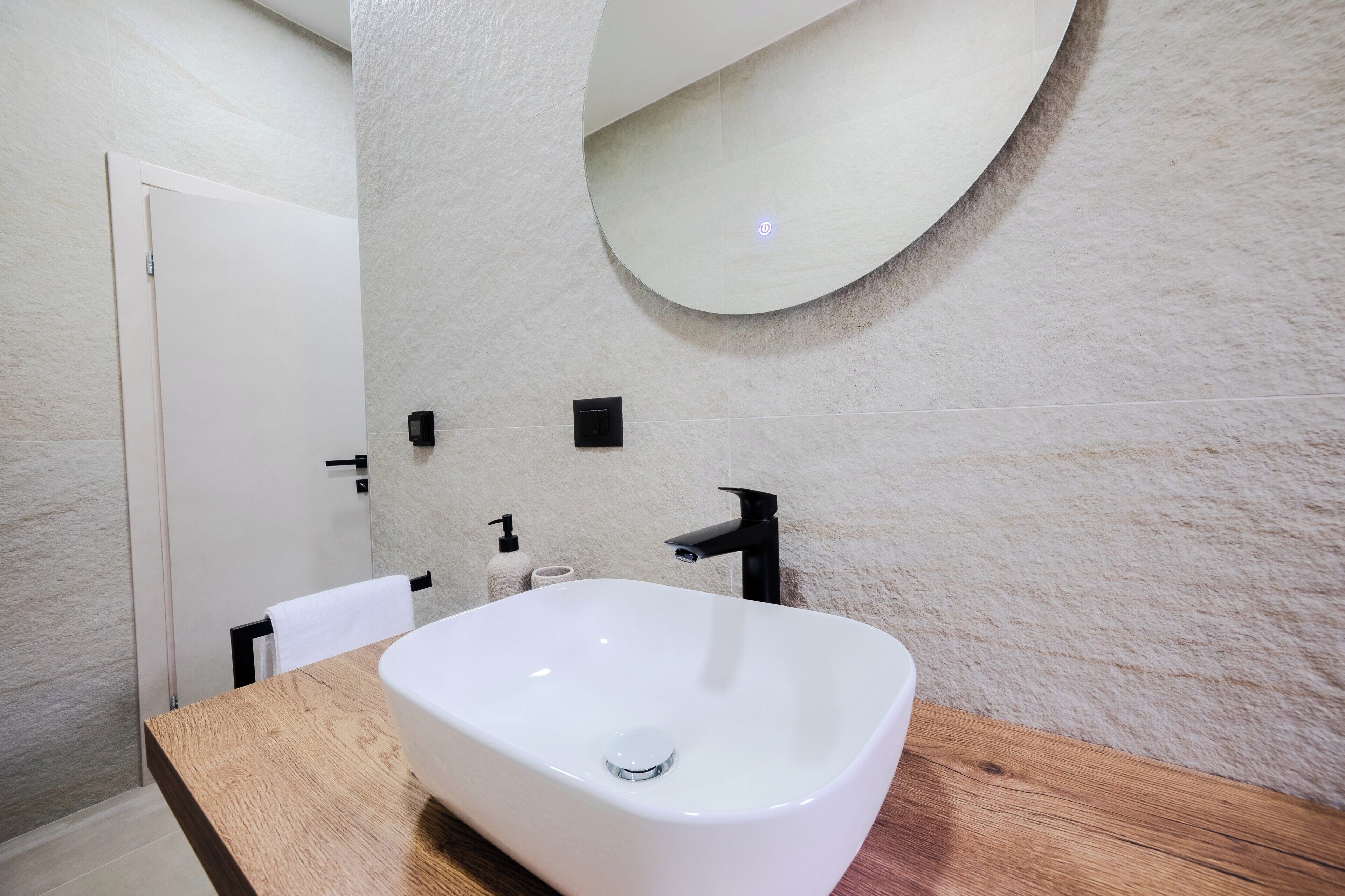 Une salle de bain avec un lavabo blanc, un plan de toilette en bois, un miroir et un porte-serviettes.